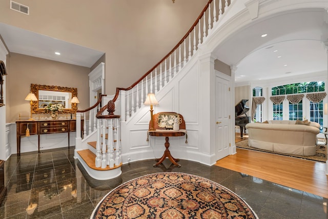 foyer featuring decorative columns, hardwood / wood-style flooring, and a towering ceiling