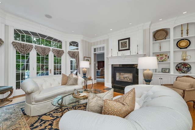 living room featuring light wood-type flooring, crown molding, and built in features