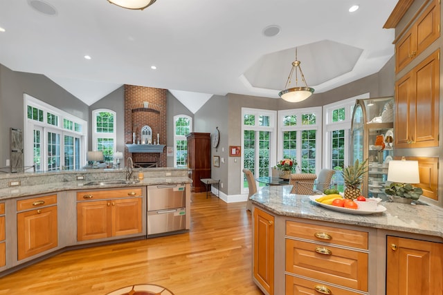 kitchen with light hardwood / wood-style floors, light stone countertops, decorative light fixtures, and a fireplace