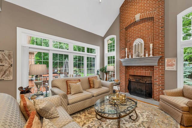 living room featuring high vaulted ceiling, a fireplace, and a healthy amount of sunlight