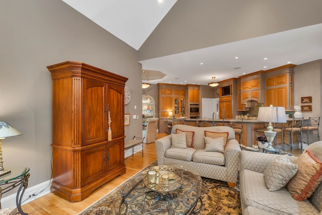 living room featuring lofted ceiling and light hardwood / wood-style floors