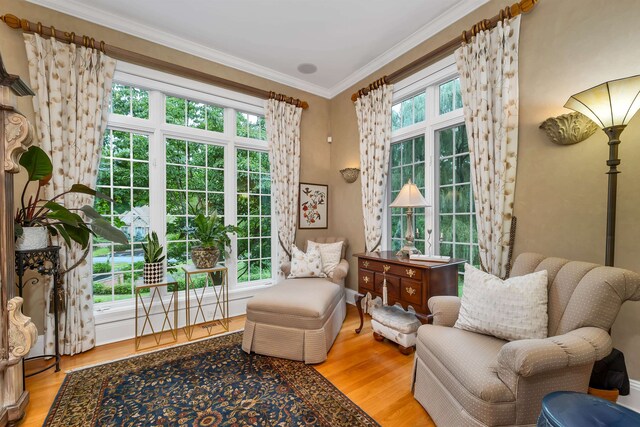 living area featuring crown molding, a healthy amount of sunlight, and hardwood / wood-style floors