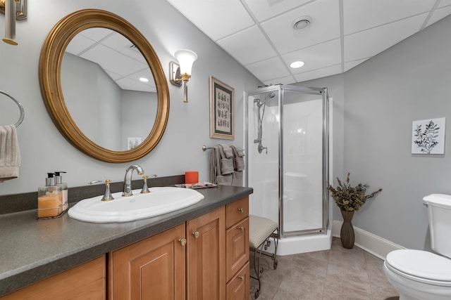 bathroom with toilet, a shower with shower door, and a drop ceiling