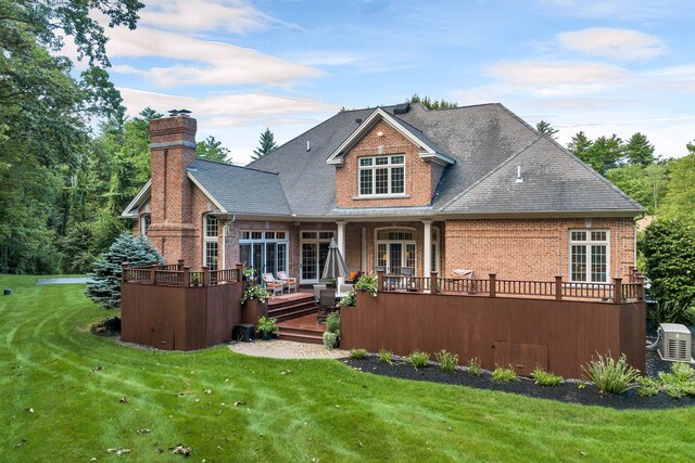 rear view of property with a wooden deck and a lawn