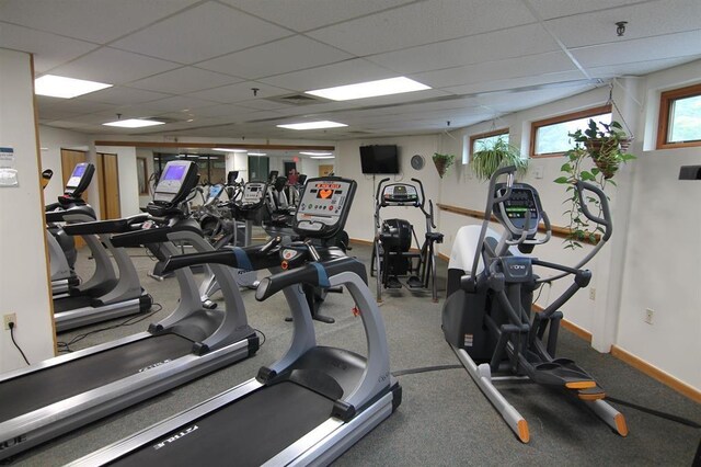 gym featuring baseboards and a drop ceiling