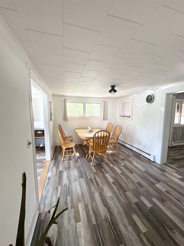 unfurnished dining area featuring dark wood-type flooring and a baseboard heating unit