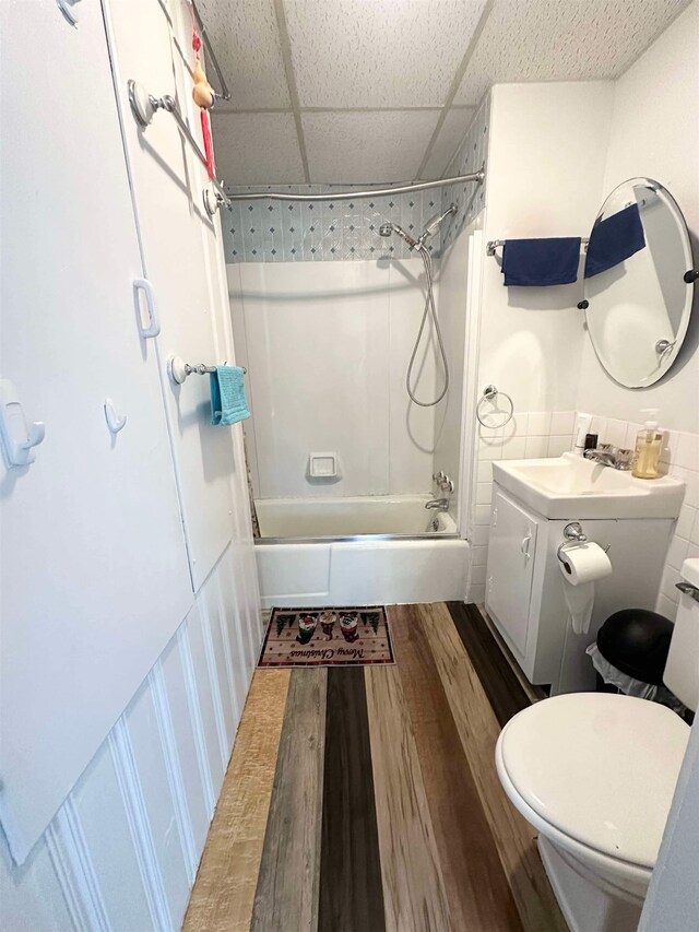 full bathroom featuring toilet, a drop ceiling, vanity, wood-type flooring, and bathing tub / shower combination