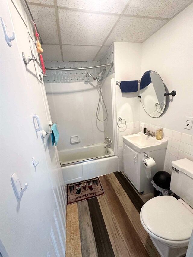 full bathroom featuring vanity, wood-type flooring, toilet, a paneled ceiling, and shower / bathing tub combination