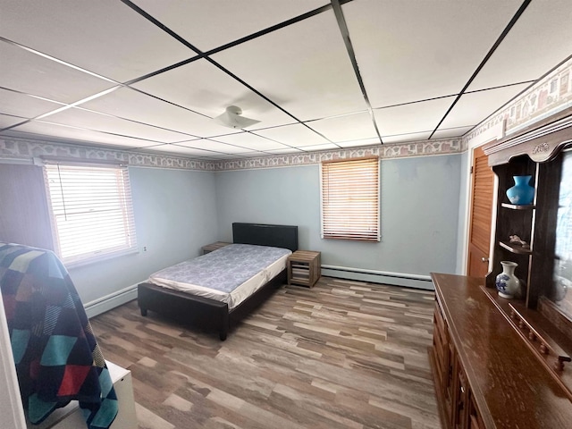 bedroom featuring a baseboard heating unit and hardwood / wood-style flooring