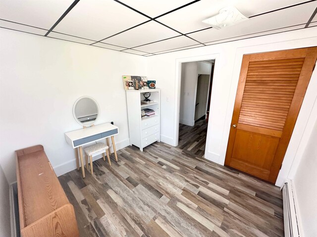 interior space featuring a baseboard heating unit, hardwood / wood-style flooring, and a paneled ceiling