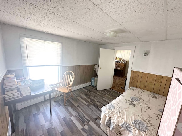 interior space featuring a drop ceiling, wooden walls, and dark hardwood / wood-style floors