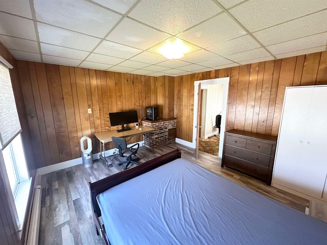 unfurnished office featuring hardwood / wood-style flooring, wood walls, and a paneled ceiling