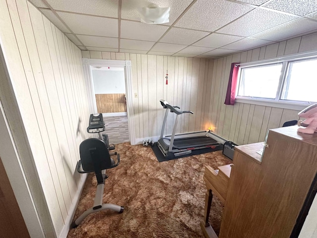 workout room with wooden walls, carpet, and a drop ceiling