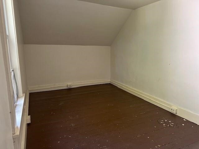 bonus room with dark hardwood / wood-style floors and vaulted ceiling