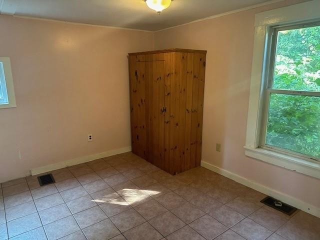 tiled empty room featuring crown molding