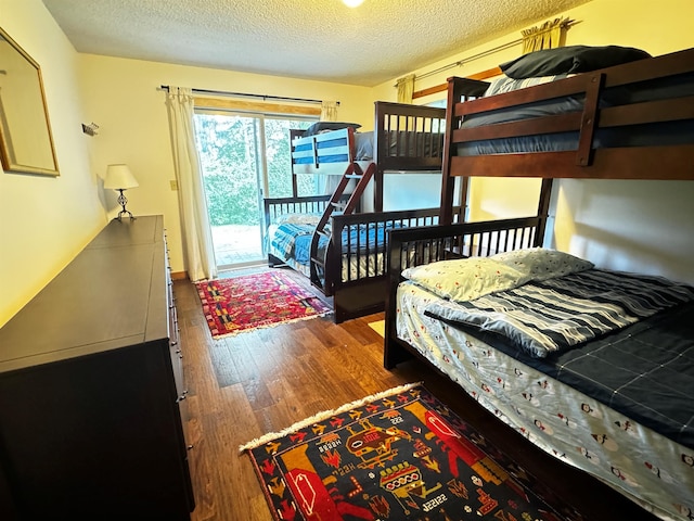 bedroom featuring dark hardwood / wood-style flooring, access to exterior, and a textured ceiling