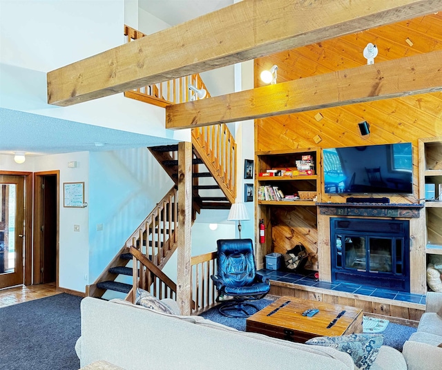 carpeted living room with beam ceiling, a fireplace, built in shelves, and a towering ceiling