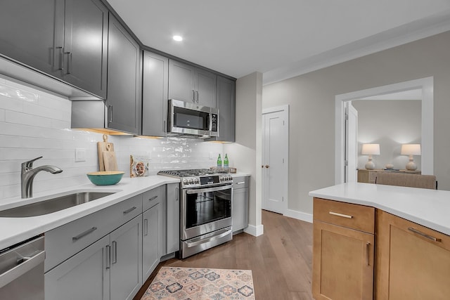 kitchen featuring sink, gray cabinetry, backsplash, stainless steel appliances, and light hardwood / wood-style floors