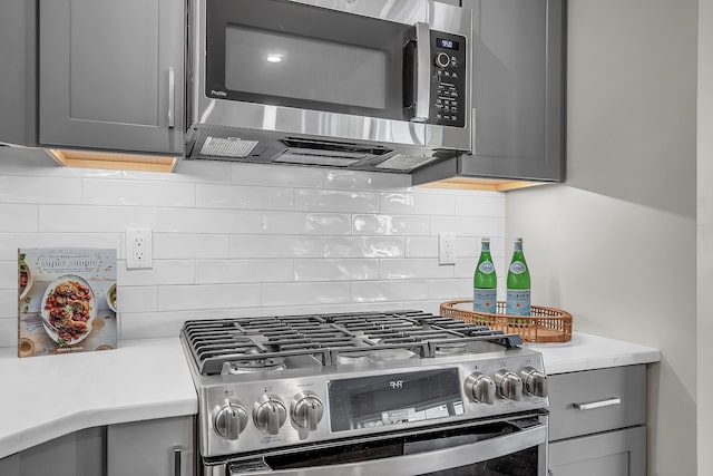 kitchen with stainless steel appliances, backsplash, and gray cabinetry