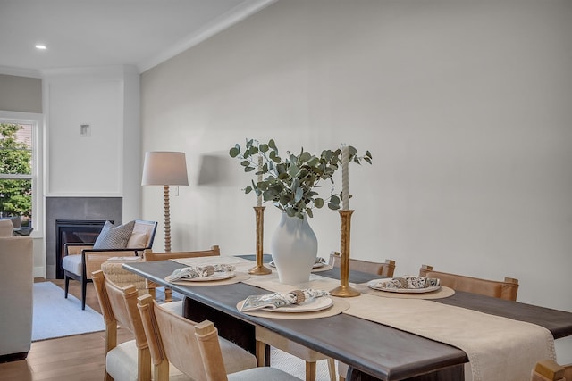 dining space with wood-type flooring and a tile fireplace