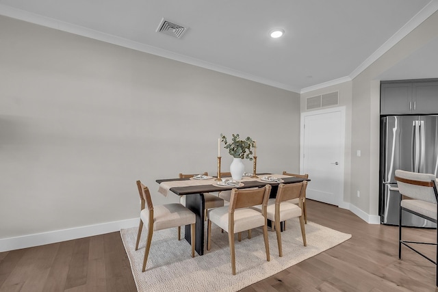 dining area featuring ornamental molding and light hardwood / wood-style flooring