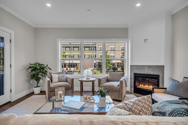 living room with a tile fireplace, hardwood / wood-style flooring, and crown molding