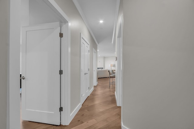 hallway with light hardwood / wood-style flooring and crown molding