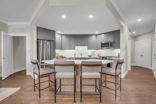 kitchen featuring an island with sink, a breakfast bar, appliances with stainless steel finishes, and light hardwood / wood-style flooring