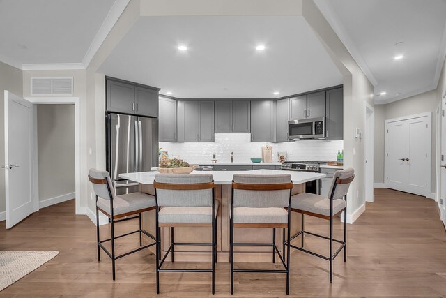 55 Pointe Pl # 106, Dover, NH 03820 - kitchen with visible vents, a breakfast bar, light countertops, ornamental molding, and appliances with stainless steel finishes