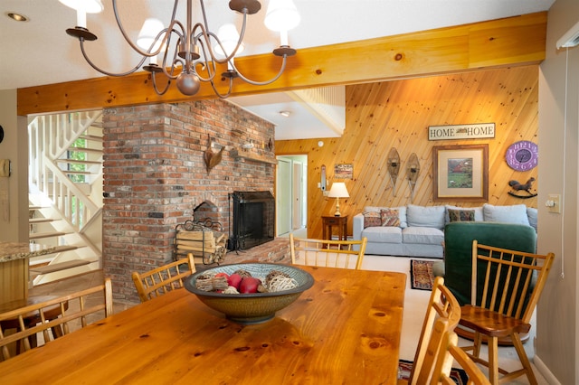 dining area featuring a fireplace, a chandelier, and wooden walls