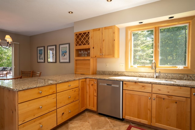 kitchen featuring plenty of natural light, stainless steel dishwasher, kitchen peninsula, and light stone counters