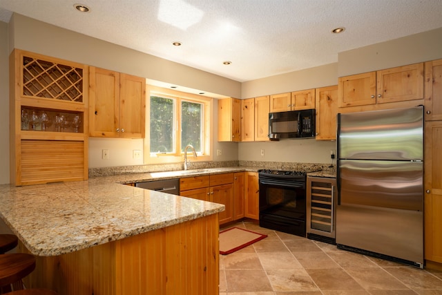 kitchen with a textured ceiling, kitchen peninsula, stainless steel appliances, and sink