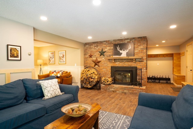 living room with a textured ceiling, hardwood / wood-style floors, and a fireplace