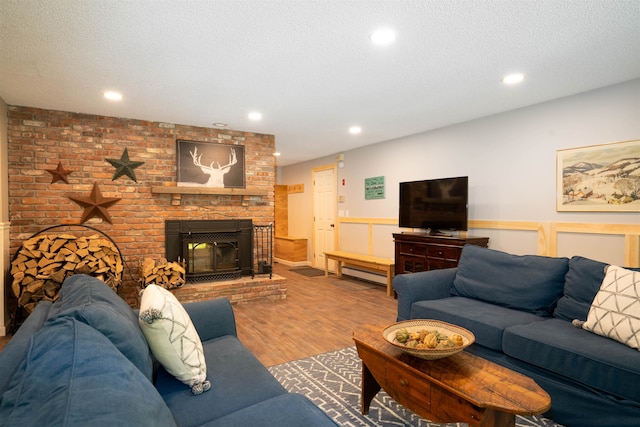 living room featuring a textured ceiling, a baseboard heating unit, hardwood / wood-style flooring, and a fireplace