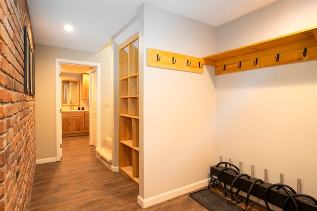 mudroom with dark hardwood / wood-style floors, sink, and brick wall