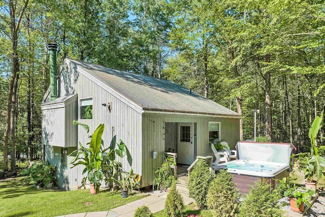 view of outdoor structure featuring a hot tub and a lawn