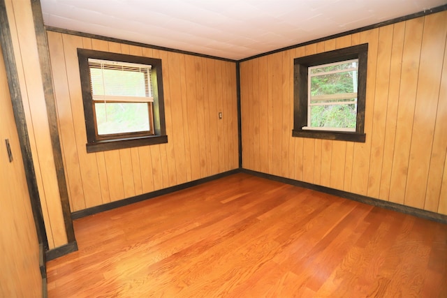 empty room featuring plenty of natural light, wooden walls, and hardwood / wood-style flooring