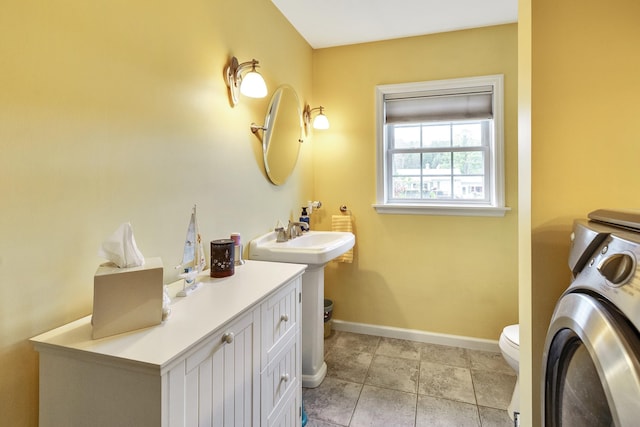 bathroom with tile patterned floors, baseboards, toilet, and washer / dryer