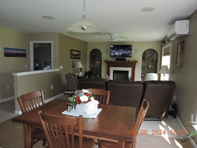 dining area featuring a high end fireplace, a wall unit AC, light tile patterned floors, and ceiling fan