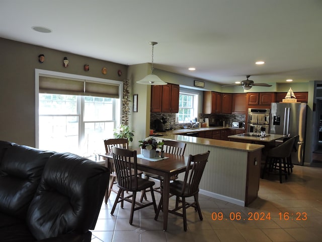 kitchen with appliances with stainless steel finishes, tasteful backsplash, hanging light fixtures, kitchen peninsula, and ceiling fan