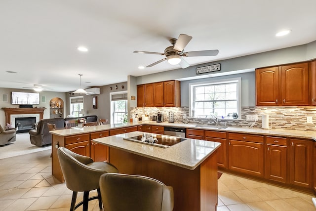 kitchen with light stone counters, black electric stovetop, a peninsula, and a glass covered fireplace