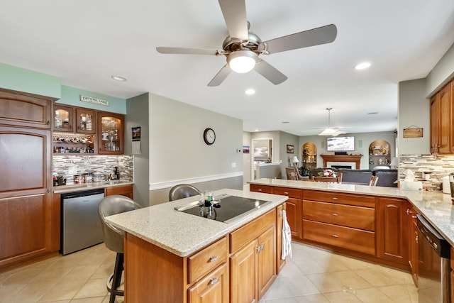 kitchen featuring stainless steel dishwasher, a kitchen breakfast bar, black electric stovetop, and a kitchen island