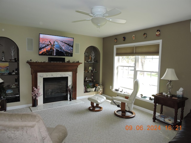 carpeted living room with ceiling fan and a premium fireplace