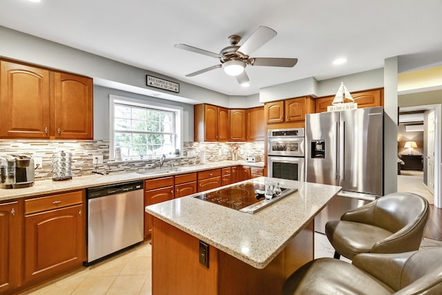 kitchen featuring tasteful backsplash, a kitchen bar, light stone counters, brown cabinetry, and stainless steel appliances