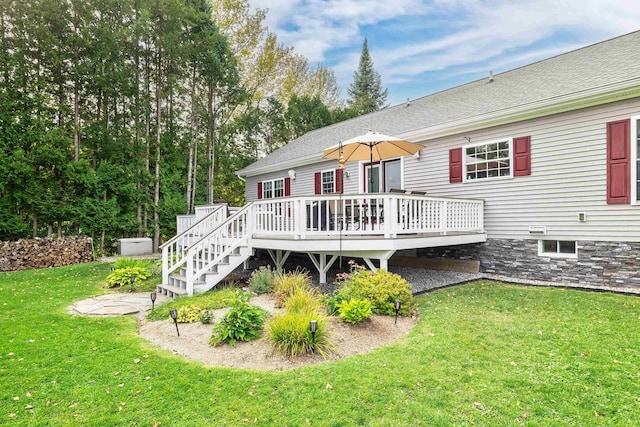 rear view of house featuring a lawn, a shingled roof, and a deck