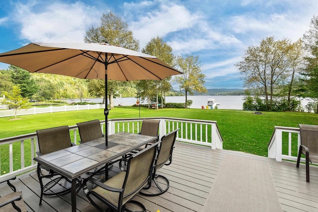 wooden deck with a lawn, fence, outdoor dining area, and a water view