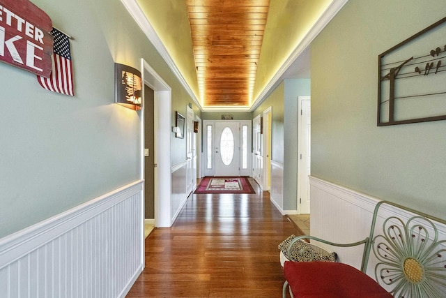 entryway with wood ceiling, wood finished floors, wainscoting, and crown molding