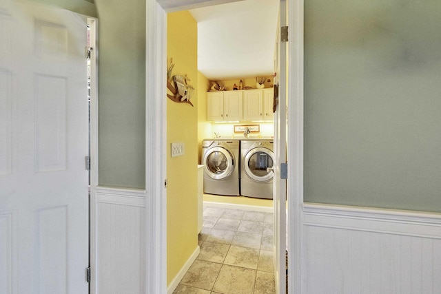 clothes washing area featuring washer and dryer, cabinet space, wainscoting, and light tile patterned floors