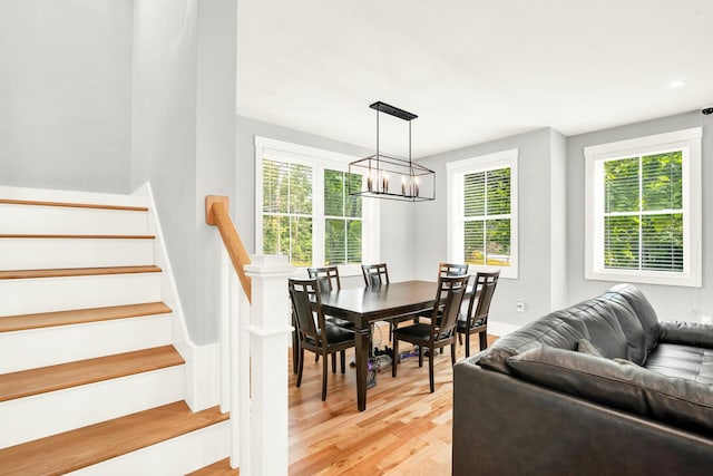 dining space featuring light wood-type flooring, a healthy amount of sunlight, and a notable chandelier