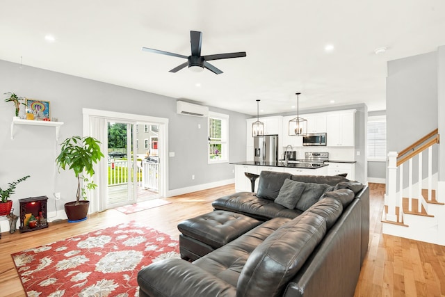 living room with light wood-type flooring, ceiling fan, an AC wall unit, and sink